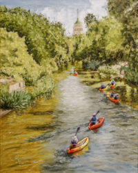 Kayakers drifting along the San Antonio River Walk surrounded by green trees